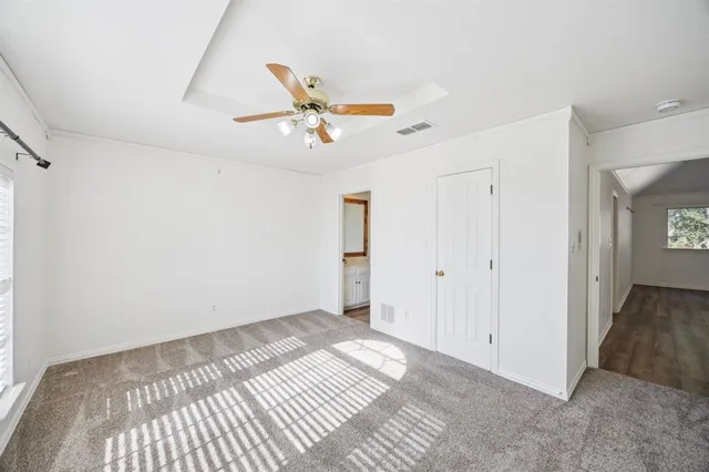 an empty room with windows and fan