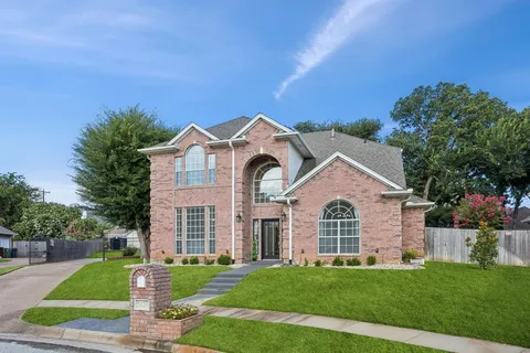 a view of a white house with a small yard and large tree