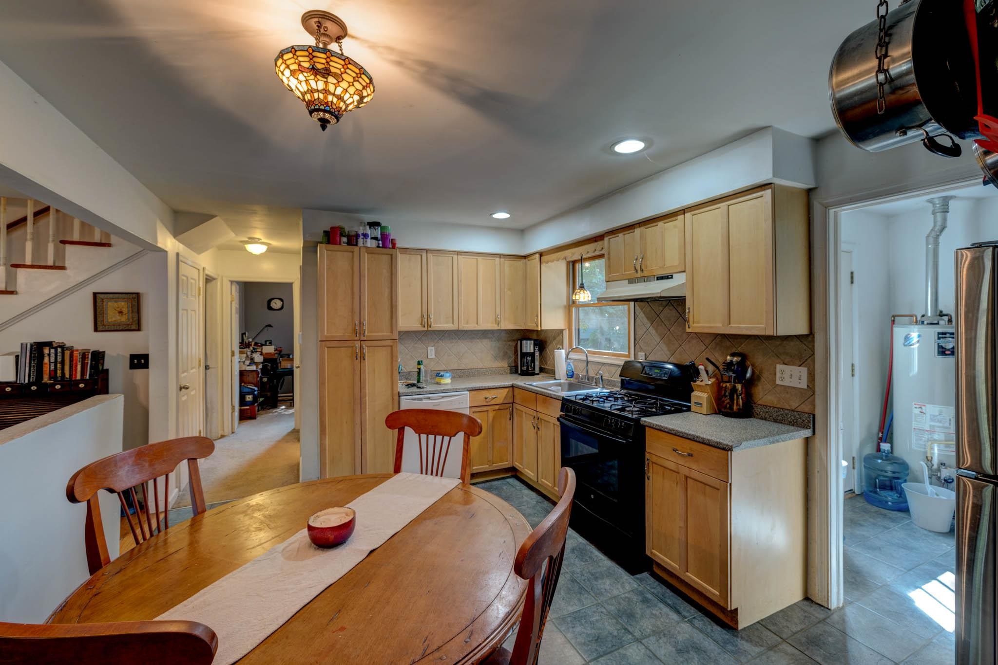 106 Delair Road Cape May, NJ 08204 - Photo 8 of 28 a kitchen with a refrigerator a stove a sink dishwasher and a dining table with wooden floor