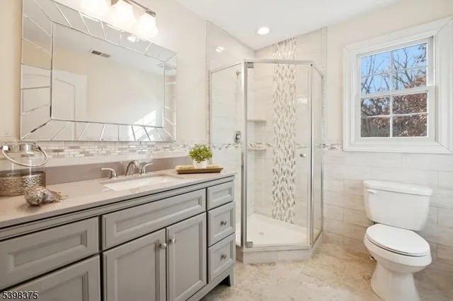 a bathroom with a shower sink vanity mirror and toilet
