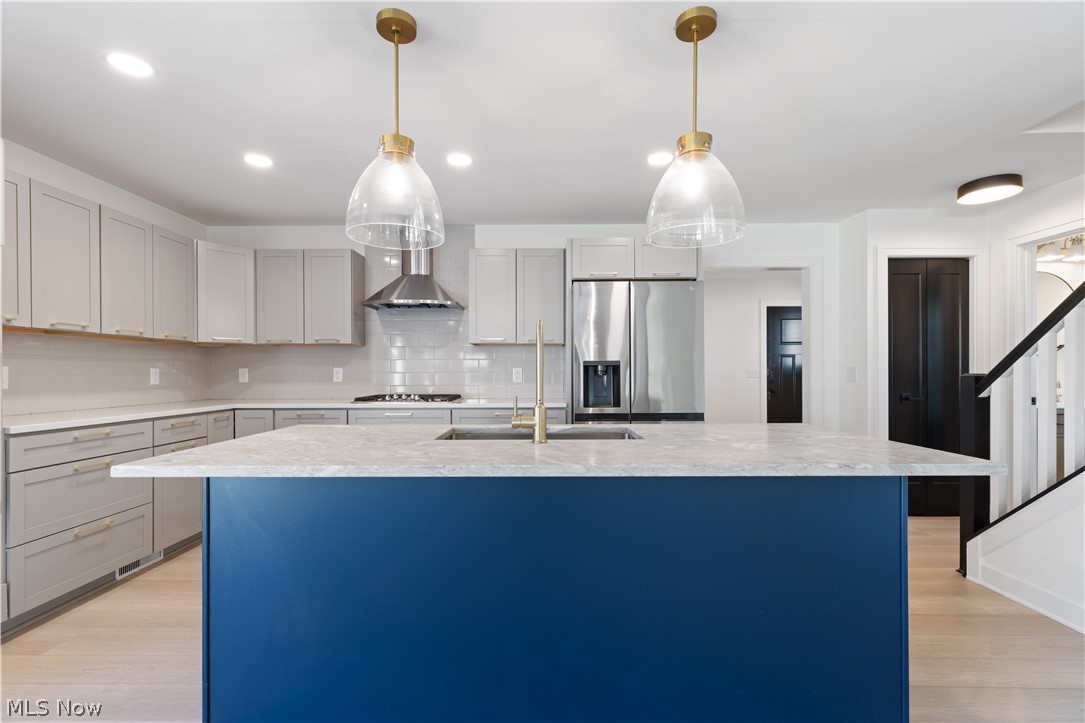 35799 Lorain Road North Ridgeville, OH 44039 - Photo 13 of 50 Kitchen with gas cooktop, light hardwood / wood-style flooring, tasteful backsplash, wall chimney range hood, and stainless steel fridge with ice dispenser
