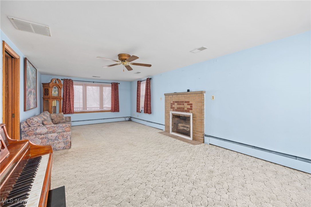 9952 Sterling Road Rittman, OH 44270 - Photo 9 of 28 Living room with a fireplace, light carpet, a ceiling fan, and a baseboard heating unit