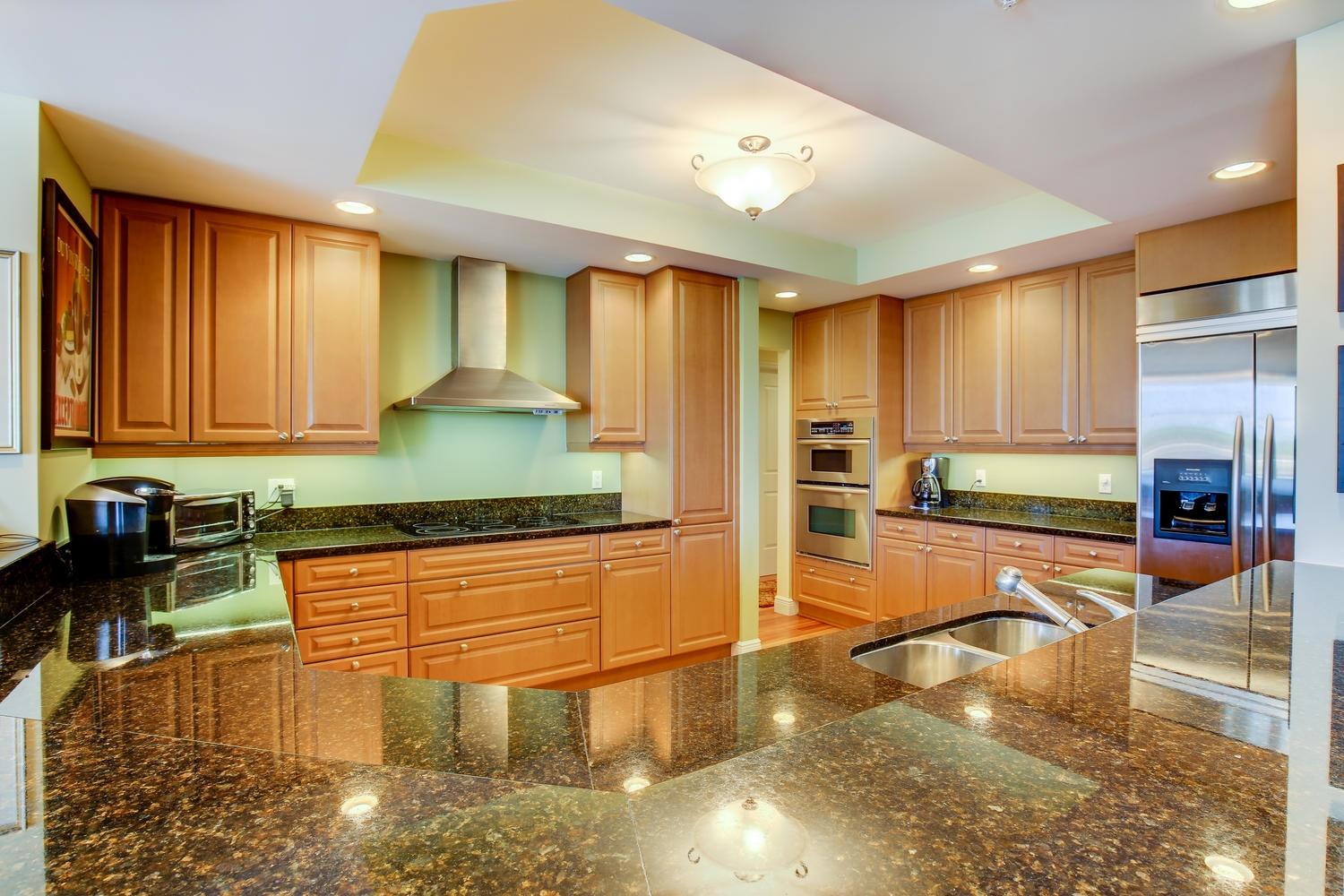 700 Highway 1, Unit 103 Jupiter, FL 33477 - Photo 14 of 36 a kitchen with stainless steel appliances granite countertop a refrigerator a stove and a sink with wooden floor
