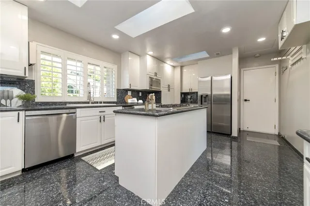 a kitchen with kitchen island granite countertop a sink appliances cabinets and counter space