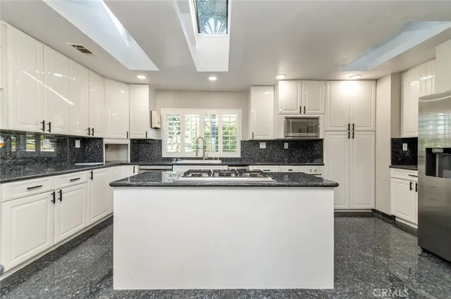 a large kitchen with stainless steel appliances granite countertop a stove a sink and a refrigerator