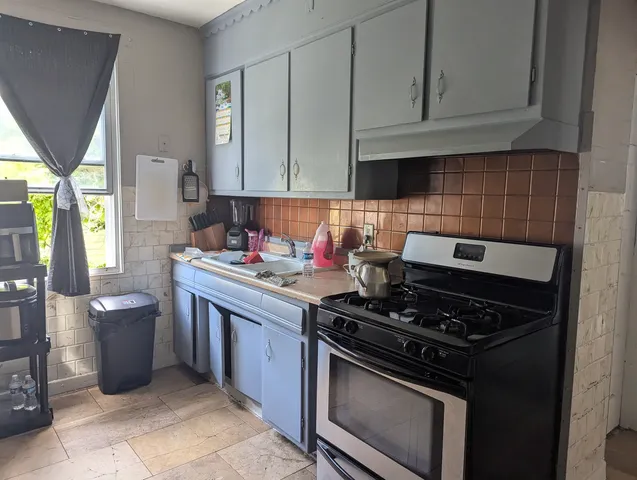 a kitchen with stainless steel appliances granite countertop a stove a sink and a white cabinets