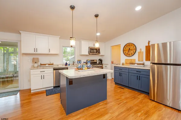 a kitchen with kitchen island granite countertop a sink a stove oven a counter space and cabinets