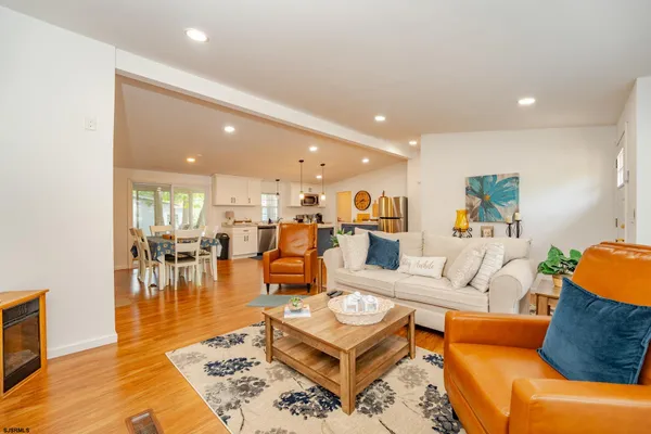 a large kitchen with stainless steel appliances granite countertop a stove top oven a sink dishwasher a dining table and chairs with wooden floor