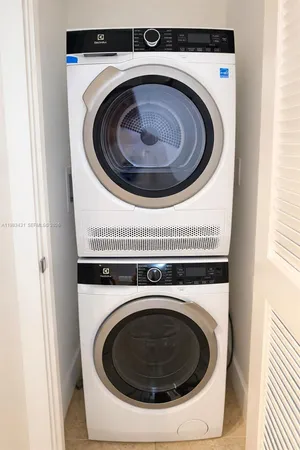 a view of a patio with couches table and chairs under an umbrella with large trees