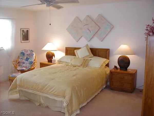 a large bed sitting in a bedroom next to a lamp with a chandelier