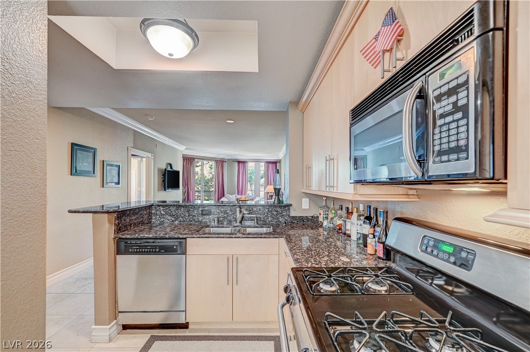 230 East Flamingo Road, Unit 333 Las Vegas, NV 89169 - Photo 23 of 61 Granite countertops and light wood cabinetry anchor this functional cooking space overlooking the main living area.