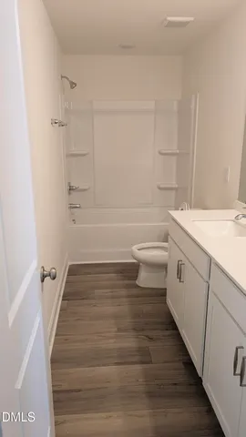 an empty room with wooden floor cabinet and windows