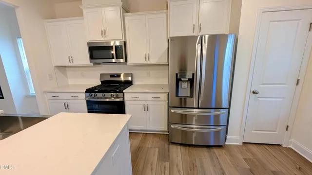 a kitchen with stainless steel appliances wooden floor sink and microwave