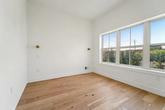 an empty room with wooden floor and windows
