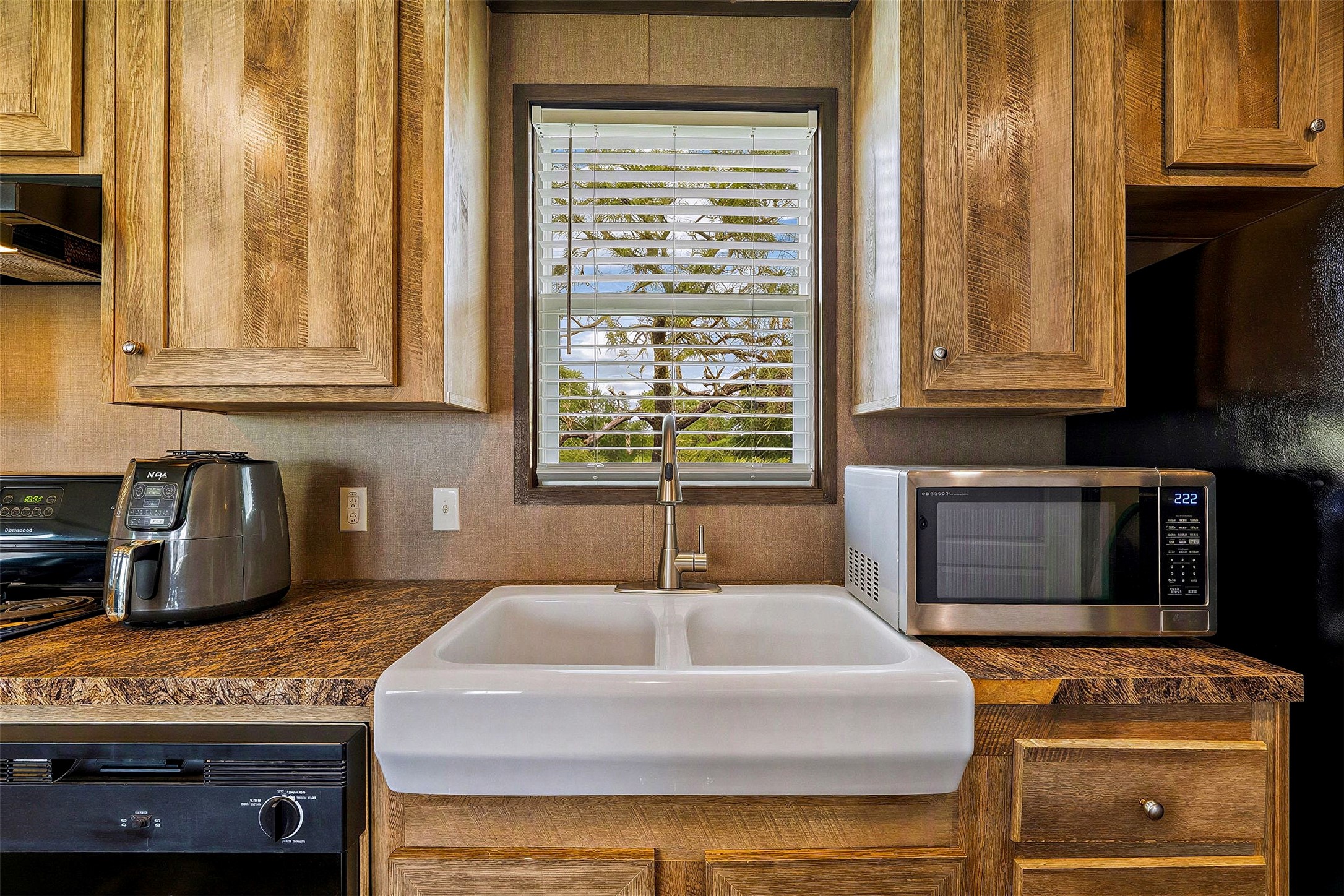 935 Lower Red Rock Road Bastrop, TX 78602 - Photo 7 of 25 Kitchen featuring a classic double basin sink, surrounded by ample cabinetry and modern appliances.