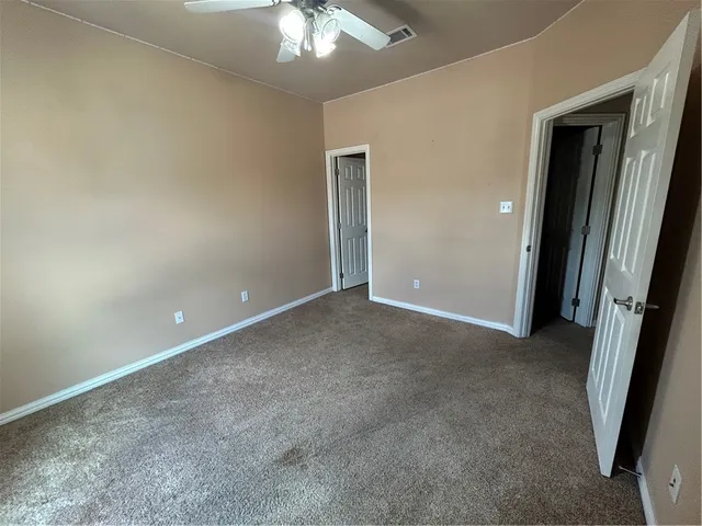 an empty room with a chandelier fan and a livingroom