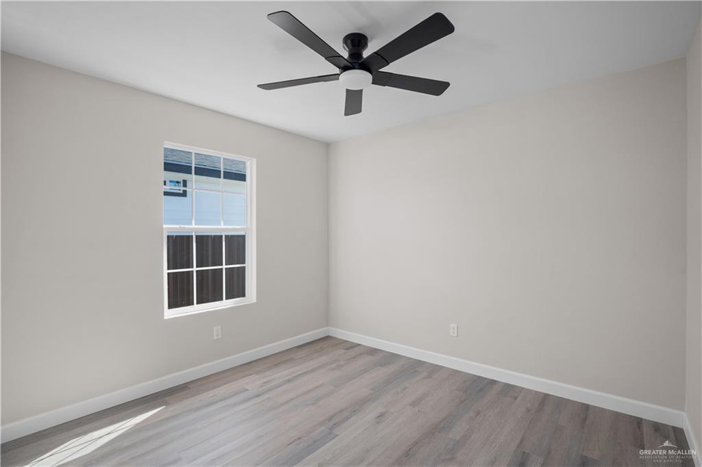 1343 Middle Street Alamo, TX 78516 - Photo 6 of 17 an empty room with wooden floor ceiling fan and windows