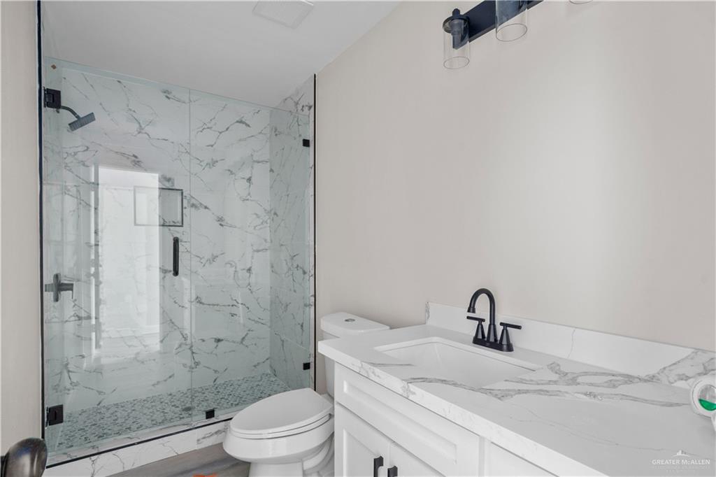 1343 Middle Street Alamo, TX 78516 - Photo 9 of 17 a bathroom with a granite countertop sink a toilet and shower