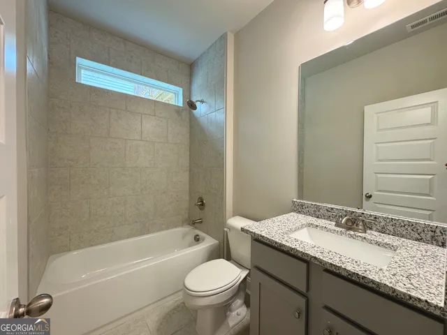 a bathroom with a granite countertop sink toilet mirror and bathtub