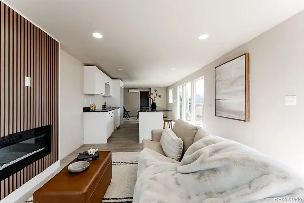 a living room with furniture a flat screen tv and a refrigerator