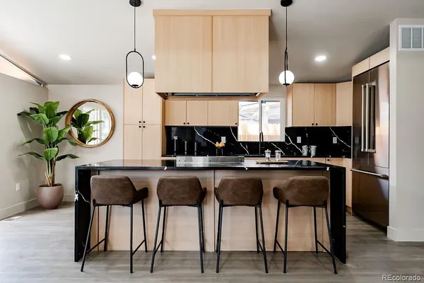 a kitchen with stainless steel appliances granite countertop sink a stove a refrigerator cabinets and chairs