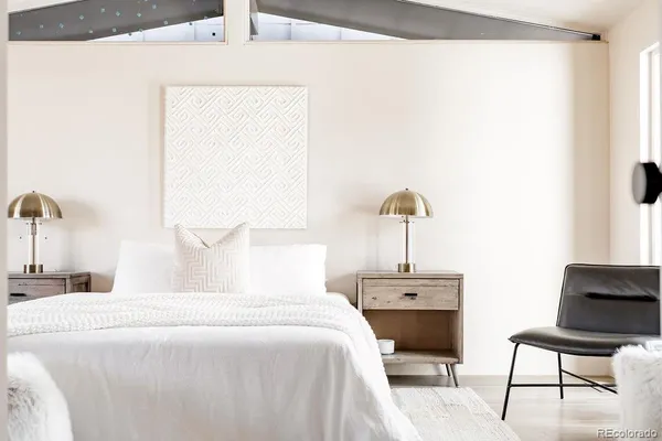 a bedroom with a bed a chair and a potted plant