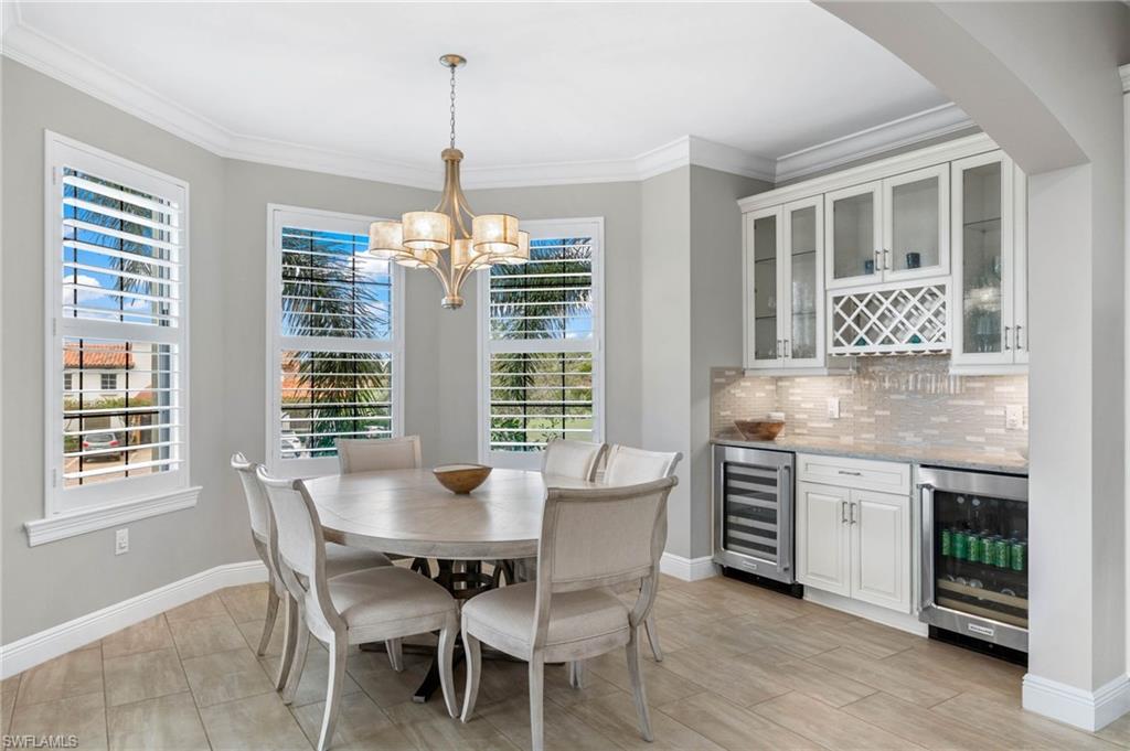 16449 Carrara Way, Unit 101 Naples, FL 34110 - Photo 12 of 35 Dining space with a decorative chandelier, custom bar area, beverage cooler, and wine cooler.