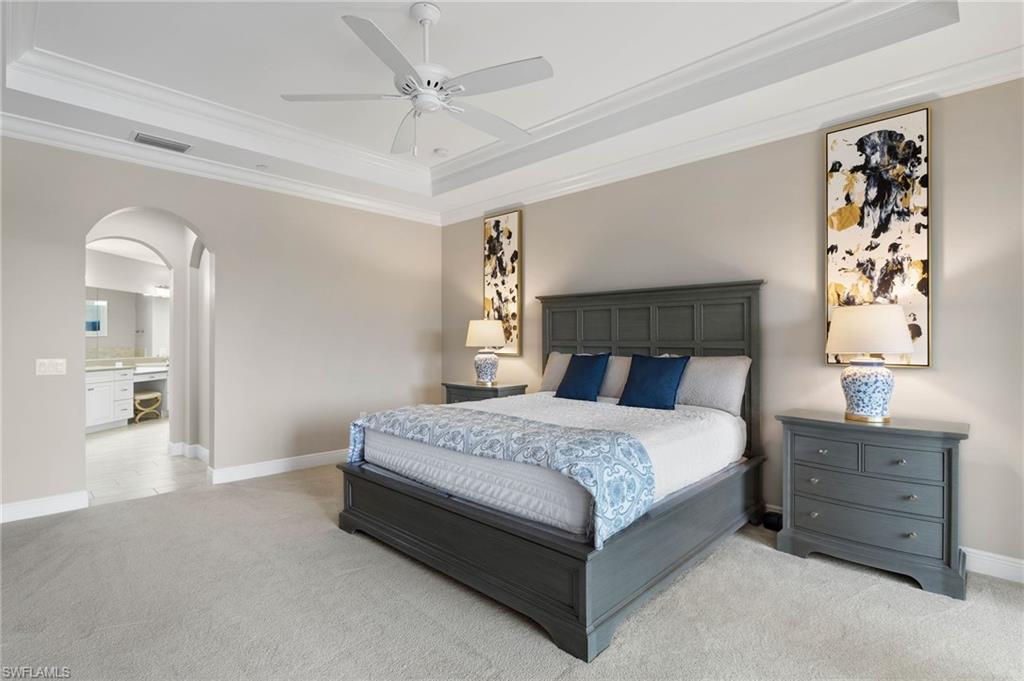 16449 Carrara Way, Unit 101 Naples, FL 34110 - Photo 15 of 35 Primary Bedroom featuring crown molding, arched walkways, and a tray ceiling.