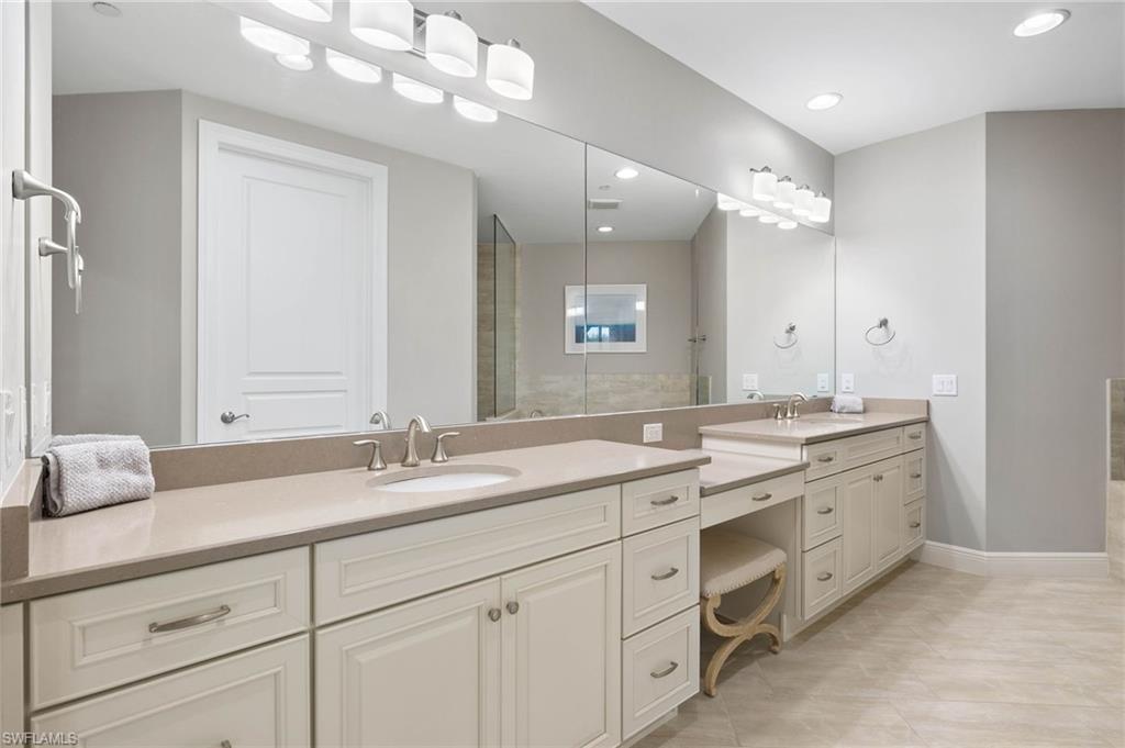 16449 Carrara Way, Unit 101 Naples, FL 34110 - Photo 16 of 35 Primary Bath with custom cabinetry, featuring built in dressing vanity and decorative lights.