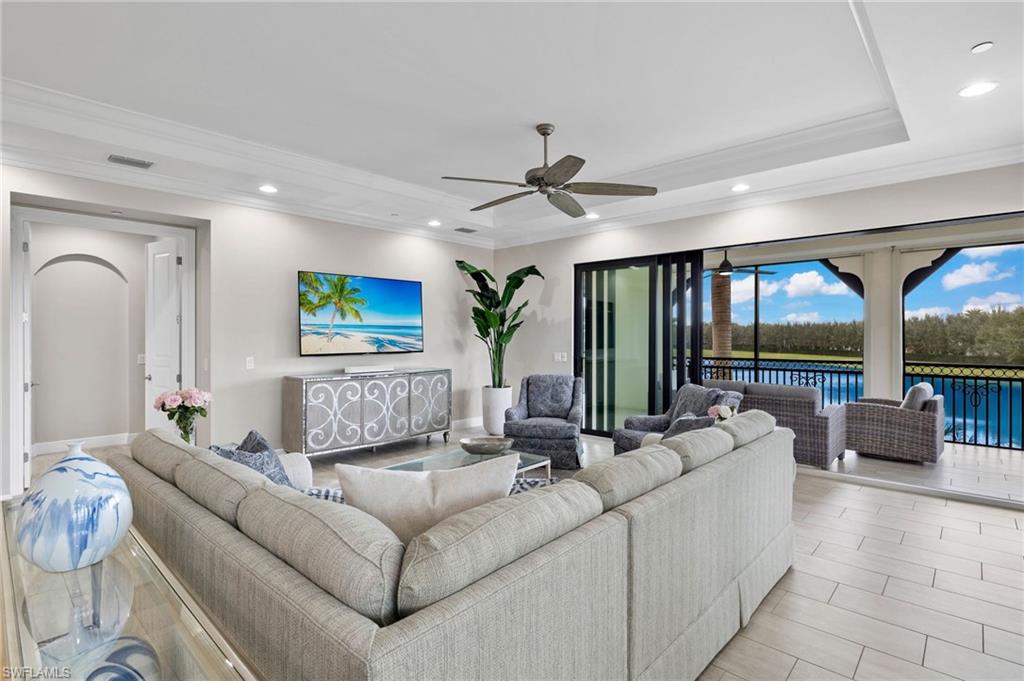 16449 Carrara Way, Unit 101 Naples, FL 34110 - Photo 4 of 35 Great Room featuring a tray ceiling, crown molding, ceiling fan, and recessed lighting.