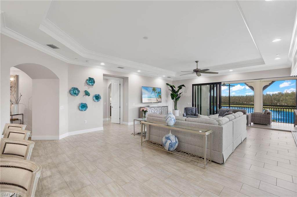 16449 Carrara Way, Unit 101 Naples, FL 34110 - Photo 6 of 35 Great Room with a ceiling fan, crown molding, and a tray ceiling.
