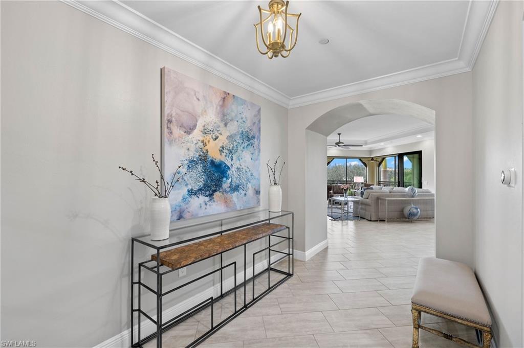 16449 Carrara Way, Unit 101 Naples, FL 34110 - Photo 7 of 35 Foyer with arched walkways, crown molding, and a notable chandelier.