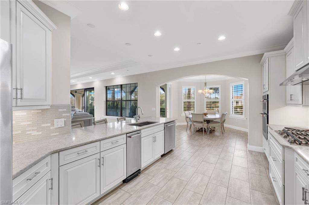 16449 Carrara Way, Unit 101 Naples, FL 34110 - Photo 9 of 35 Kitchen featuring arched walkways, appliances with stainless steel finishes, and decorative backsplash.