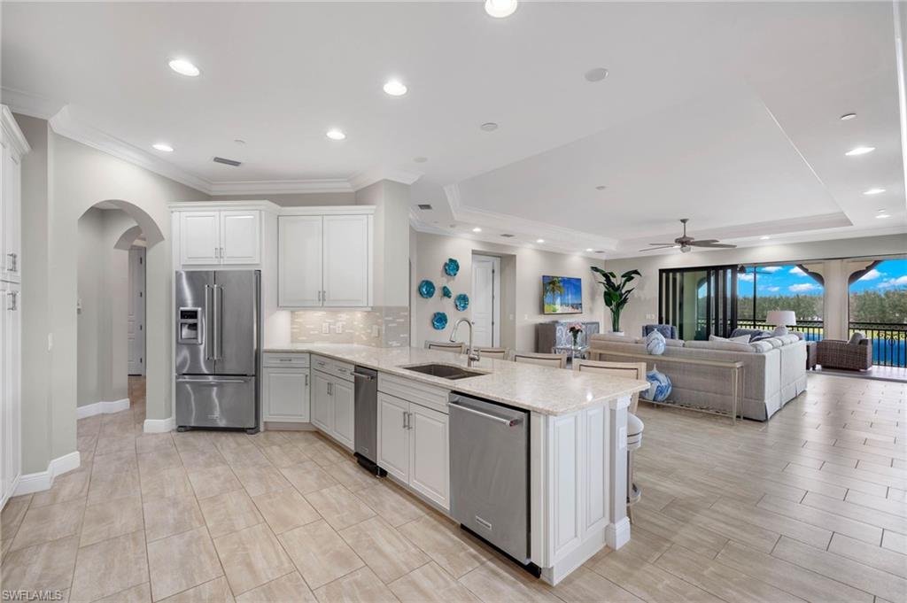 16449 Carrara Way, Unit 101 Naples, FL 34110 - Photo 10 of 35 Kitchen with a peninsula, appliances with stainless steel finishes, and decorative backsplash.
