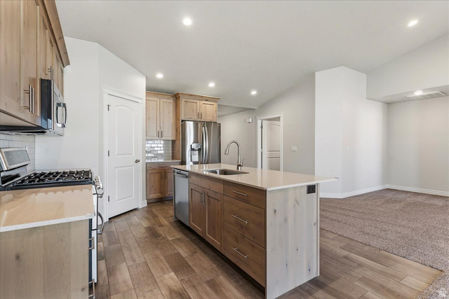 2028 West Grace Way Layton, UT 84041 - Photo 10 of 36 Kitchen featuring stainless steel appliances, tasteful backsplash, a center island with sink, wood tiled floors, and recessed lighting