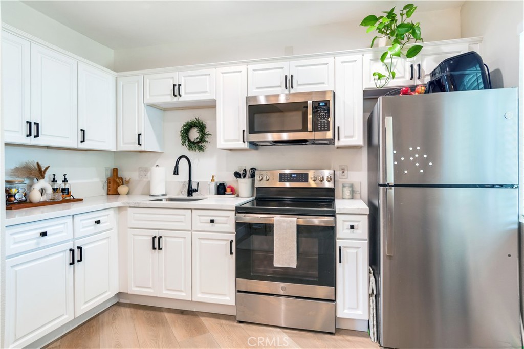 6755 Rainier Court Riverside, CA 92506 - Photo 20 of 23 a kitchen with white cabinets stainless steel appliances and wooden floor