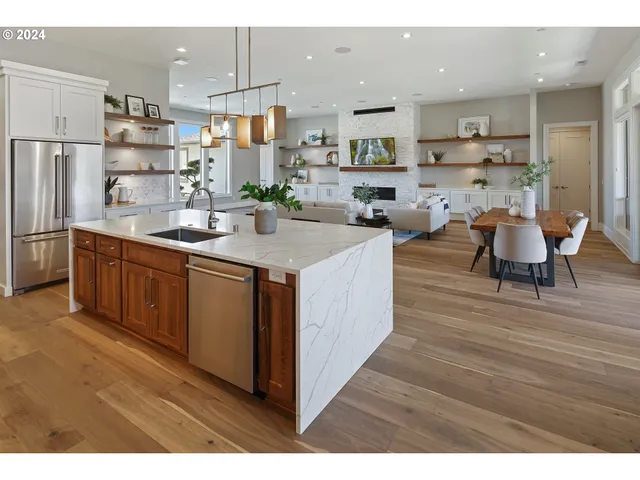 a room with stainless steel appliances kitchen island granite countertop a sink and cabinets