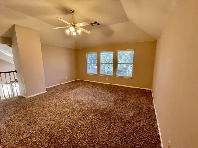 an empty room with windows and chandelier fan