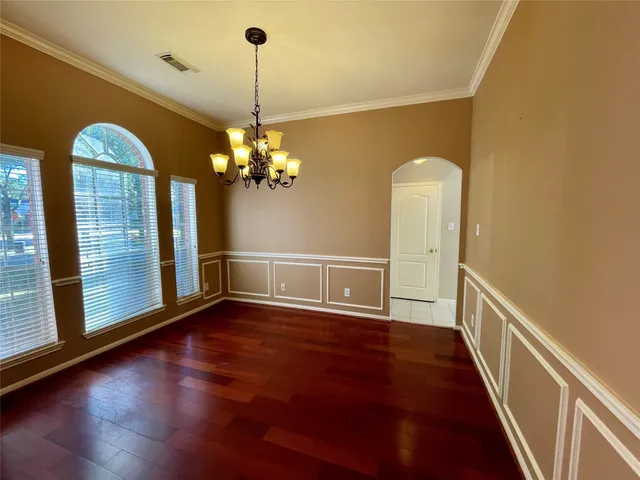 a view of a room with wooden floor chandelier and windows