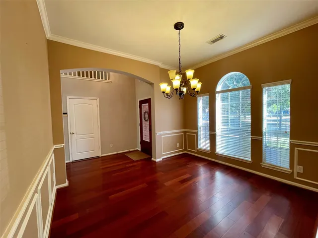 a view of a room with wooden floor chandelier and windows