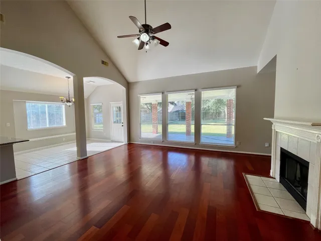a view of an empty room with wooden floor and a fireplace