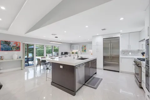 a large white kitchen with kitchen island a table and chairs in it