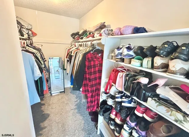 a view of walk in closet with clothes and shoes