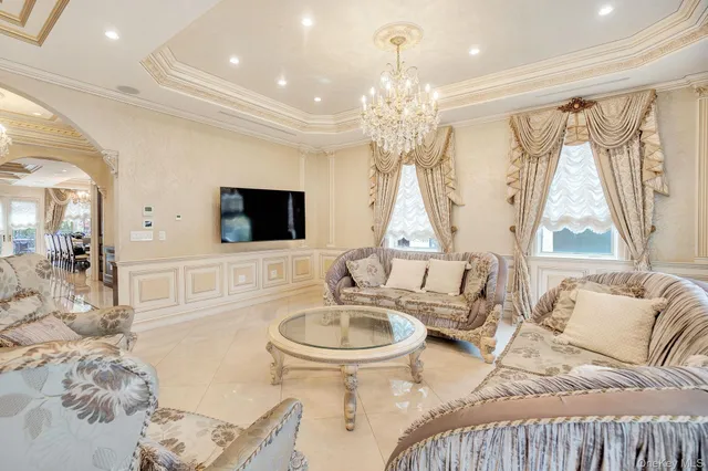 a living room with furniture a chandelier and a flat screen tv