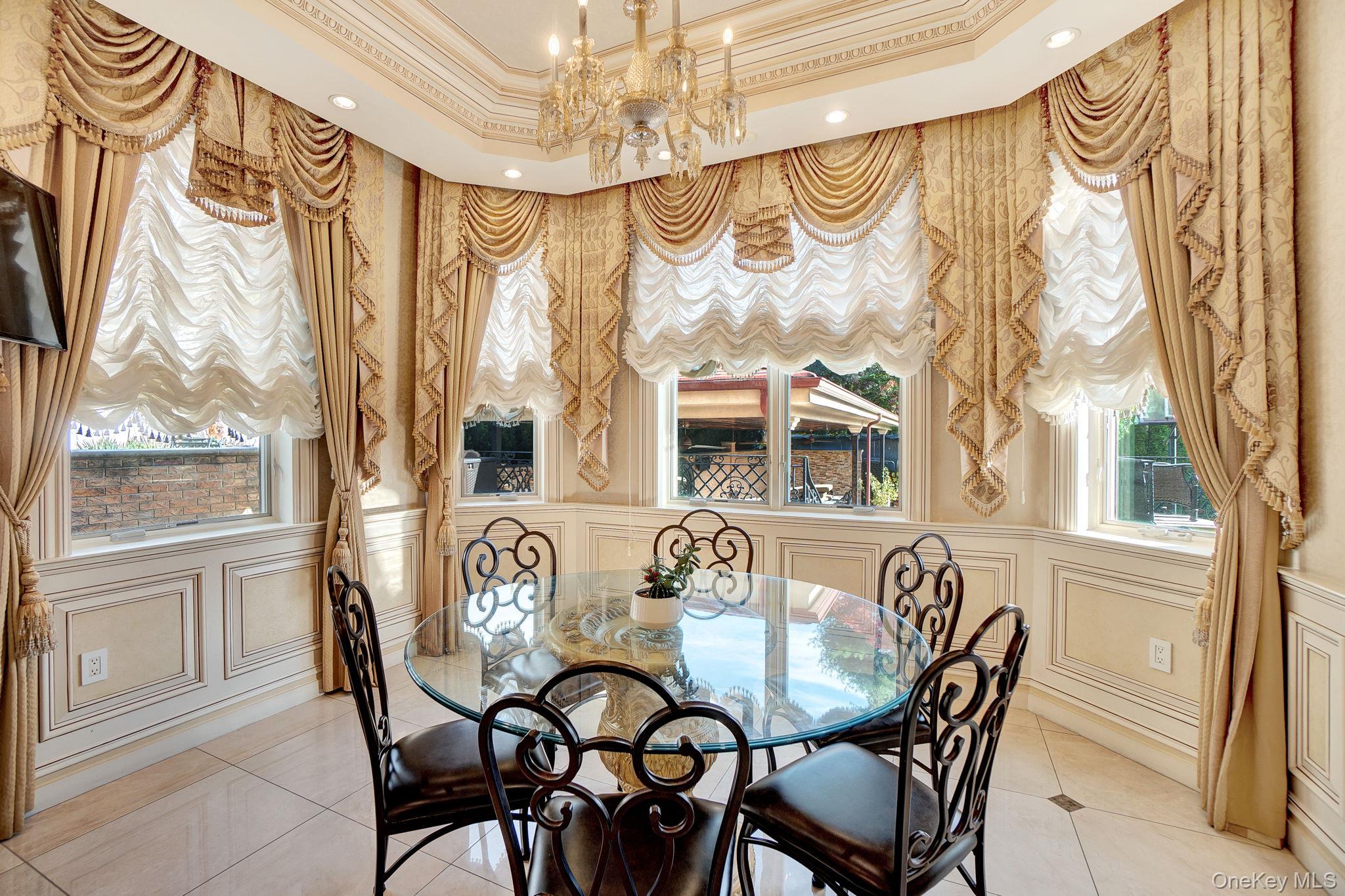 181-30 Tudor Road Queens, NY 11432 - Photo 20 of 46 Dining space with a decorative wall, a chandelier, tile patterned flooring, crown molding, and a tray ceiling