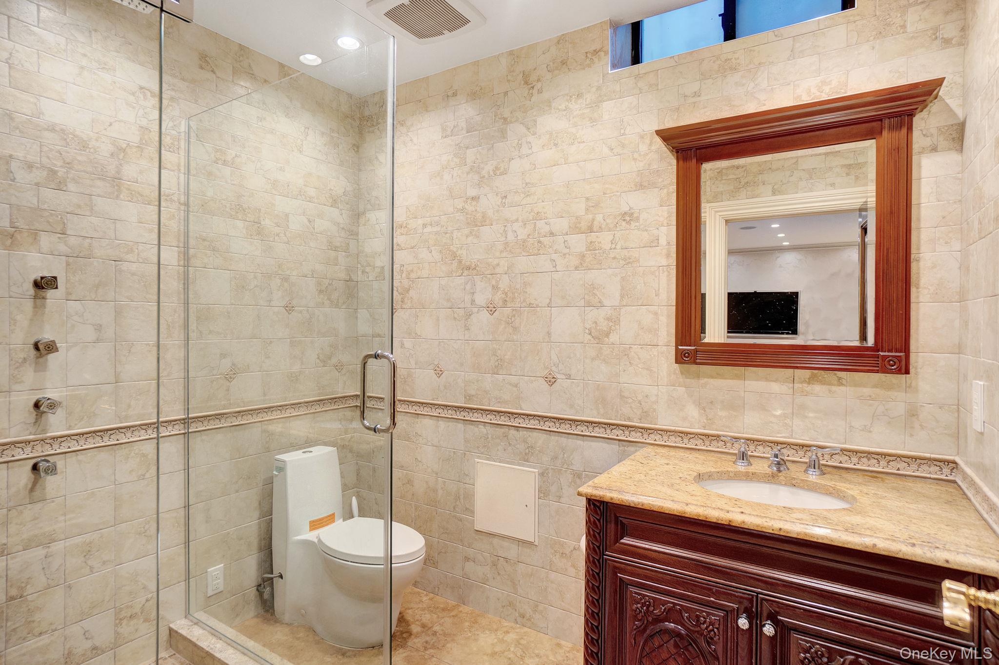 181-30 Tudor Road Queens, NY 11432 - Photo 31 of 46 Bathroom with tile walls, vanity, a shower stall, and tile patterned flooring