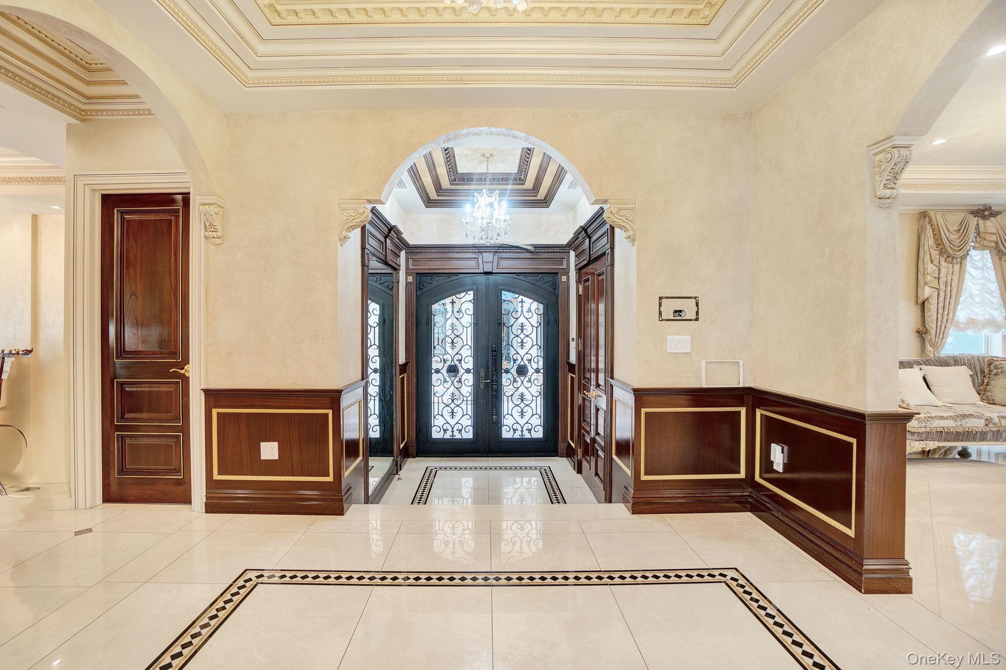 181-30 Tudor Road Queens, NY 11432 - Photo 4 of 46 Foyer featuring arched walkways, inlaid floor details, crown molding, a wainscoted wall, and a decorative wall