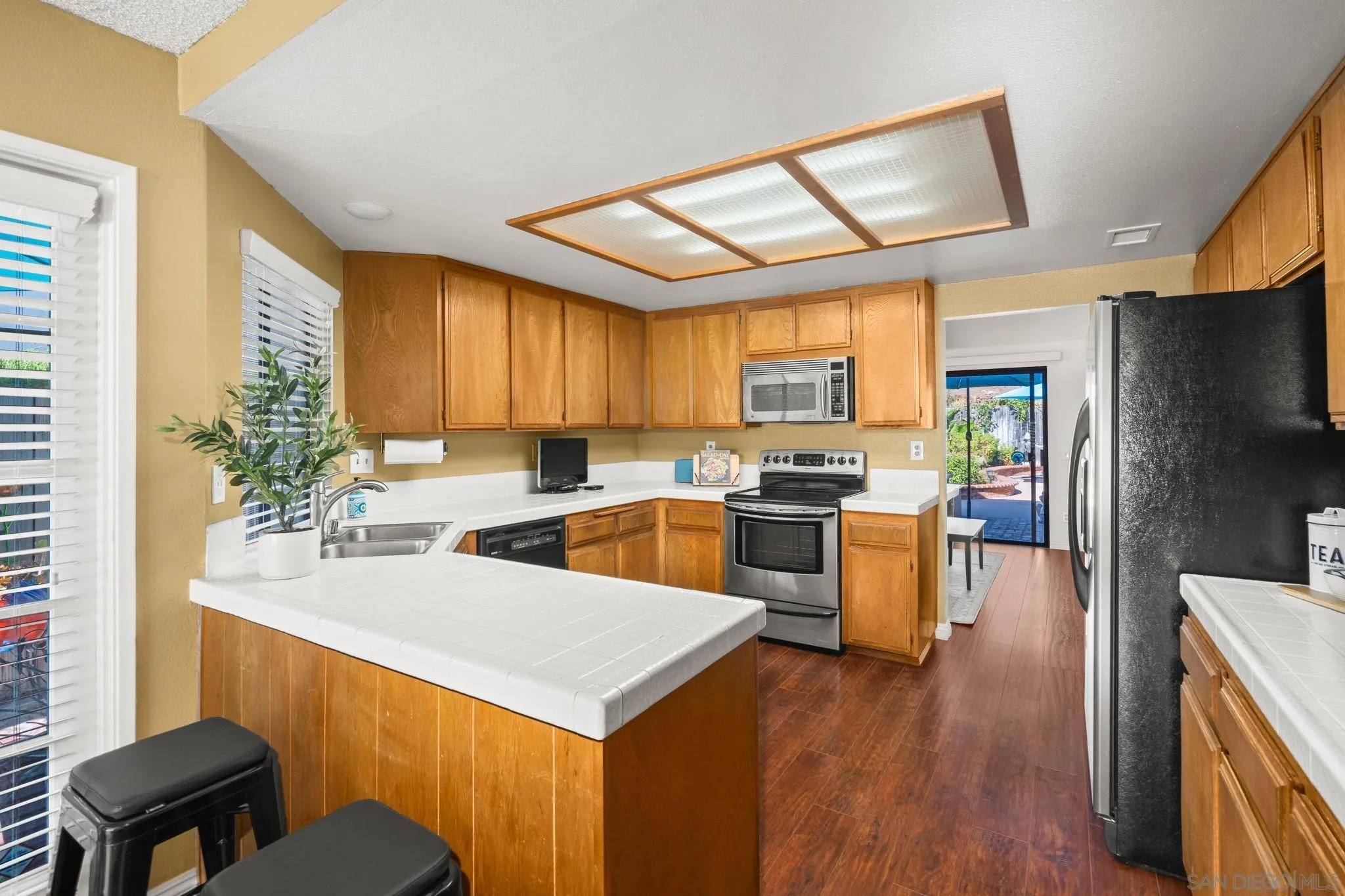 3544 Paseo Salamoner La Mesa, CA 91941 - Photo 22 of 45 a kitchen with a refrigerator a stove top oven a sink dishwasher and wooden cabinets with wooden floor