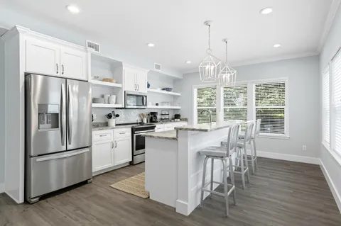 a kitchen with stainless steel appliances a dining table chairs stove and cabinets