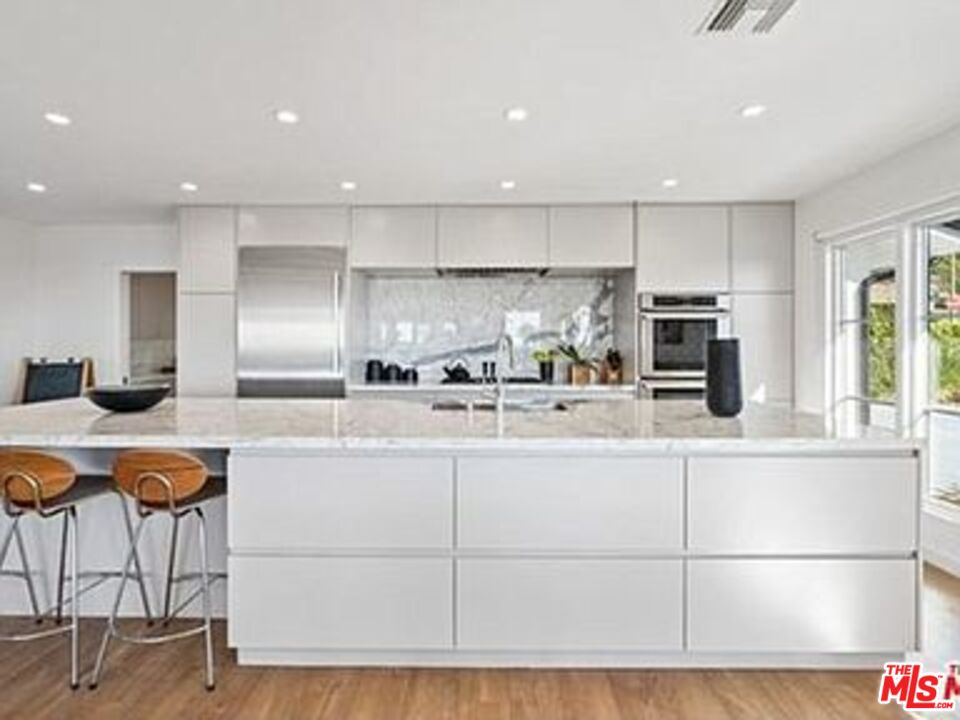 Roca Chica Drive Malibu, CA 90265 - Photo 10 of 34 a kitchen with stainless steel appliances kitchen island granite countertop a refrigerator a stove a sink and white cabinets with wooden floor